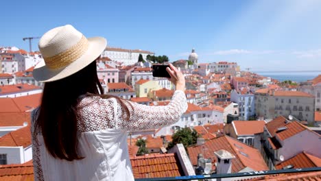 a tourist woman takes pictures of the beautiful cityscape of lisbon