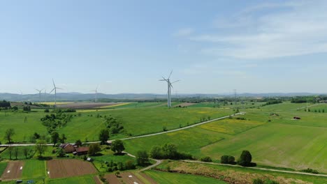 Polish-farms-and-villages-rustic-panorama-with-modern-wind-turbines-rotating-in-fields,-aerial