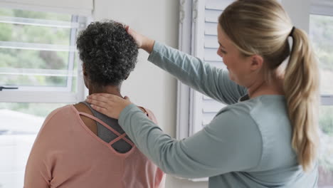 caucasian female physiotherapist checking neck of senior woman, copy space, slow motion