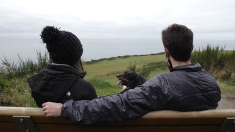 Couple-sit-on-bench-with-dog-at-Ebey's-Landing-on-Whidbey-Island