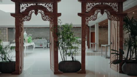 intricately carved wooden archway leading to a bright modern interior with plants