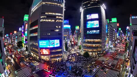 high-angle video of a bustling city intersection at night, showcasing vibrant neon lights and busy