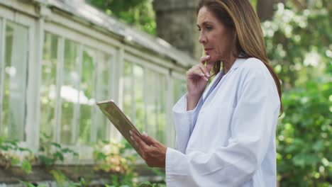 mujer usando una tableta digital en un jardín botánico
