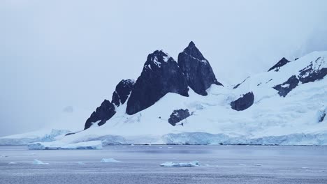 Antarctica-Winter-Mountains-on-Coast,-Coastal-Landscape-Scenery-in-Antarctic-Peninsula,-Cold-Blue-Scene-with-Glacier-Ice-and-Southern-Ocean-Sea-Water,-Mountain-Seascape-in-Beautiful-Dramatic-Scene