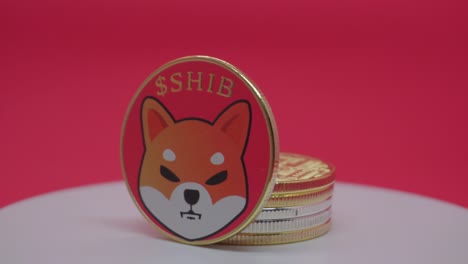 shiba inu (shib) cryptocurrency price goes down - metal shib coin is spinning in front of the red background.