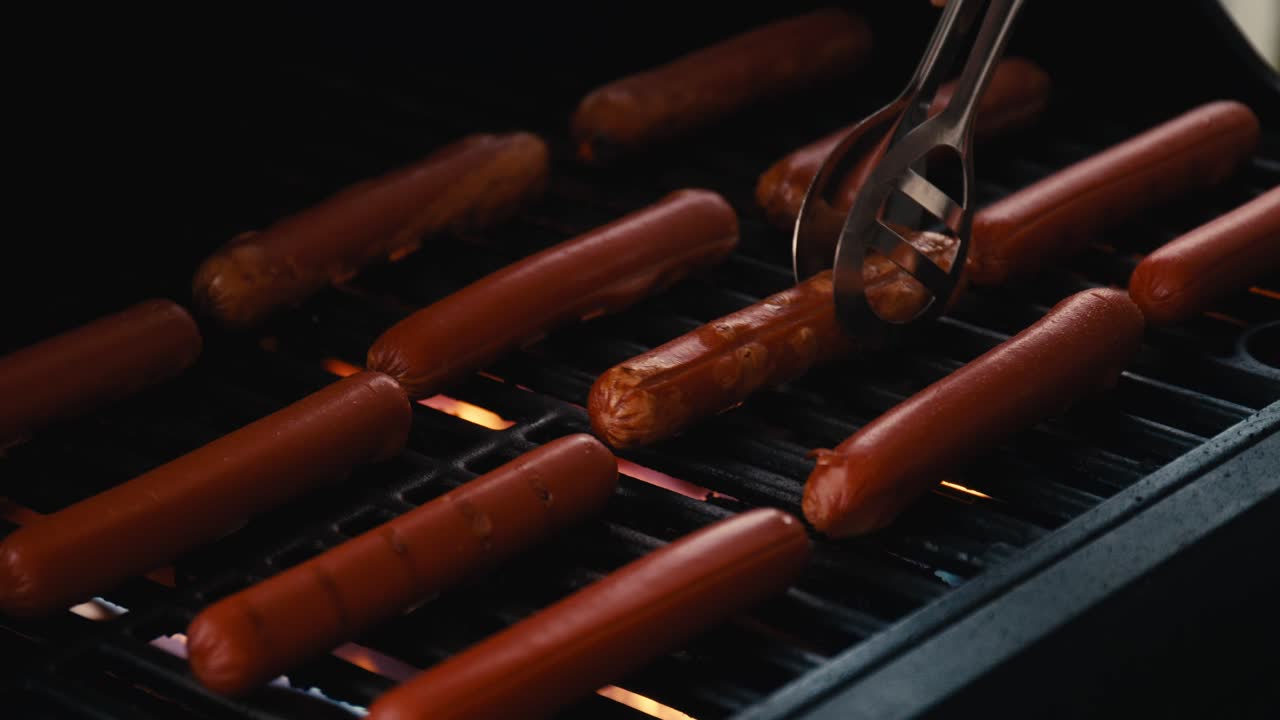 un hombre voltea varias salchichas deliciosas en una parrilla de gas