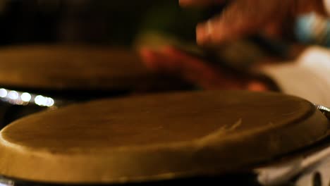 close up shot of caribbean male playing the drums at a concert at night