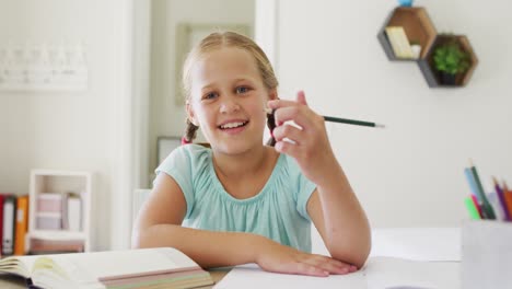 portrait of caucasian girl holding a pencil smiling looking at the camera at home