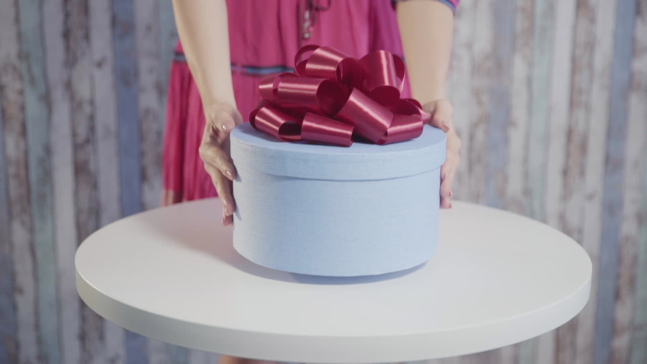 una chica con un vestido puso una caja de regalo sobre la mesa