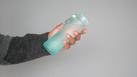 person holding a teal glass water bottle