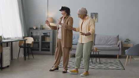 middle aged arabic woman helping a senior lady to use virtual reality headset glasses at home 2