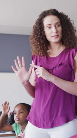 video of caucasian female school teacher and diverse school children studying in classroom