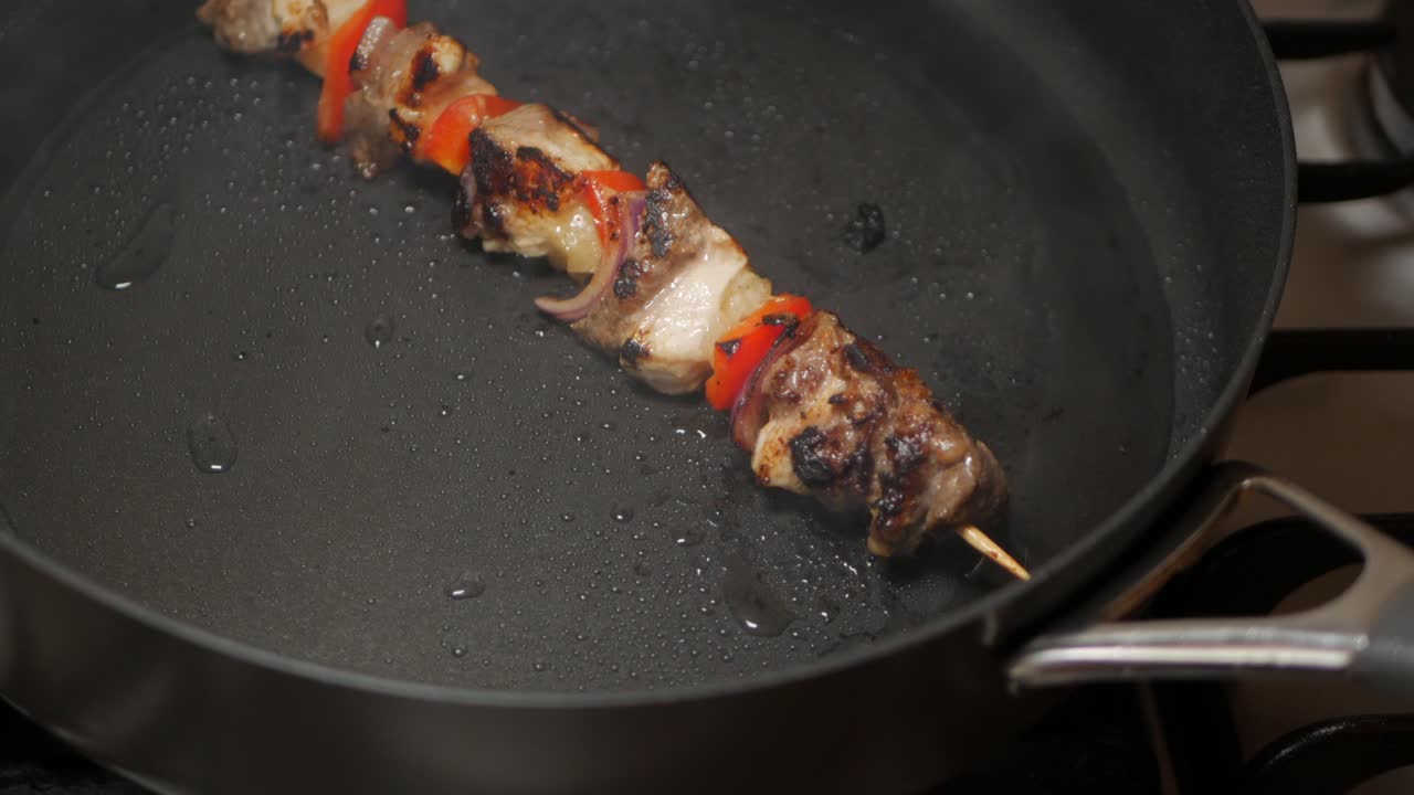Spiedino di carne e verdure cotto in una padella nera nell'olio di arachidi.