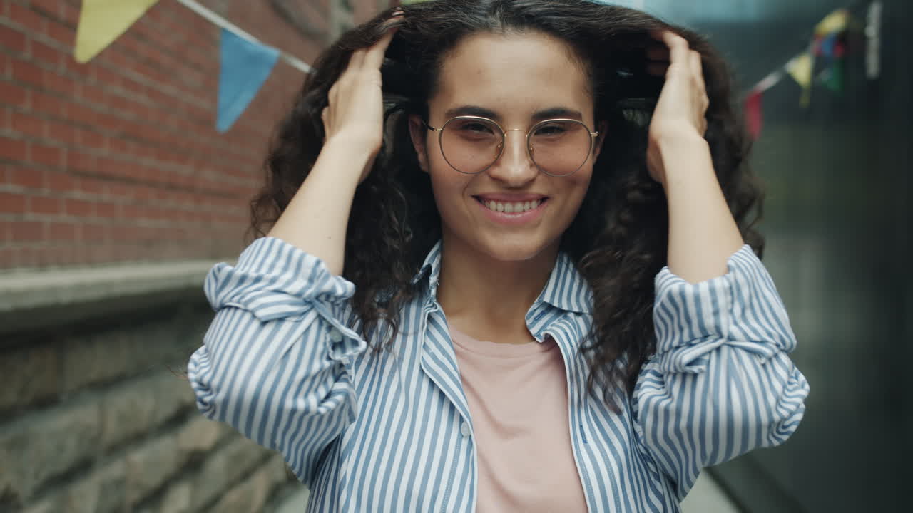 Smiling Woman with Curly Hair and Glasses in an Alley