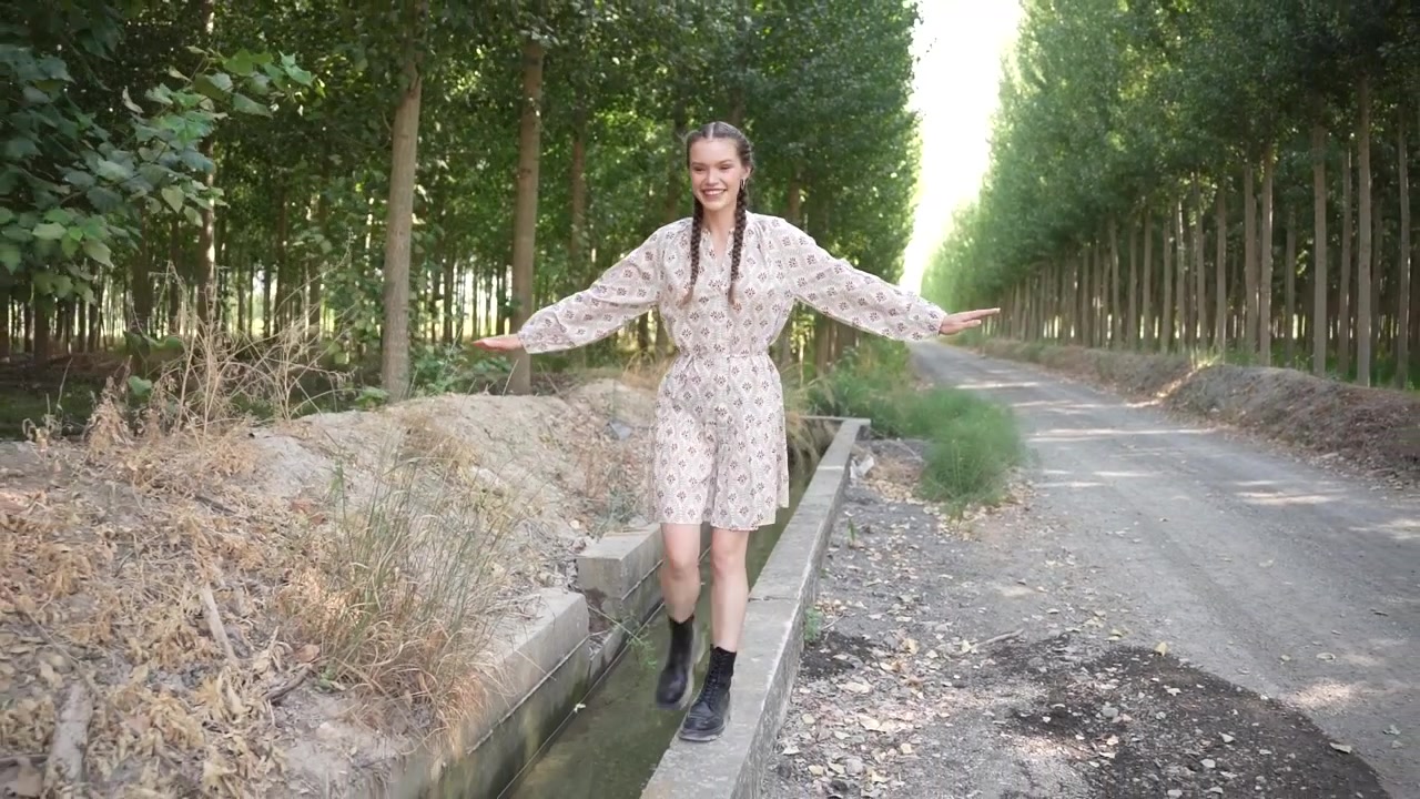 Una modella che passeggia con grazia lungo un pittoresco sentiero alberato in un contesto naturale