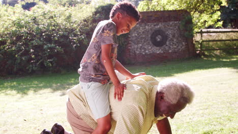 Hombre-Negro-Mayor-A-Cuatro-Patas-Con-Su-Nieto-Montando-Su-Espalda