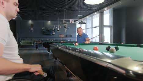 adult men with disabilities in a wheelchair play billiards in the club