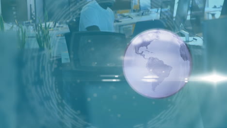 animación de un globo giratorio y procesamiento de datos sobre un hombre de negocios en el escritorio usando una computadora