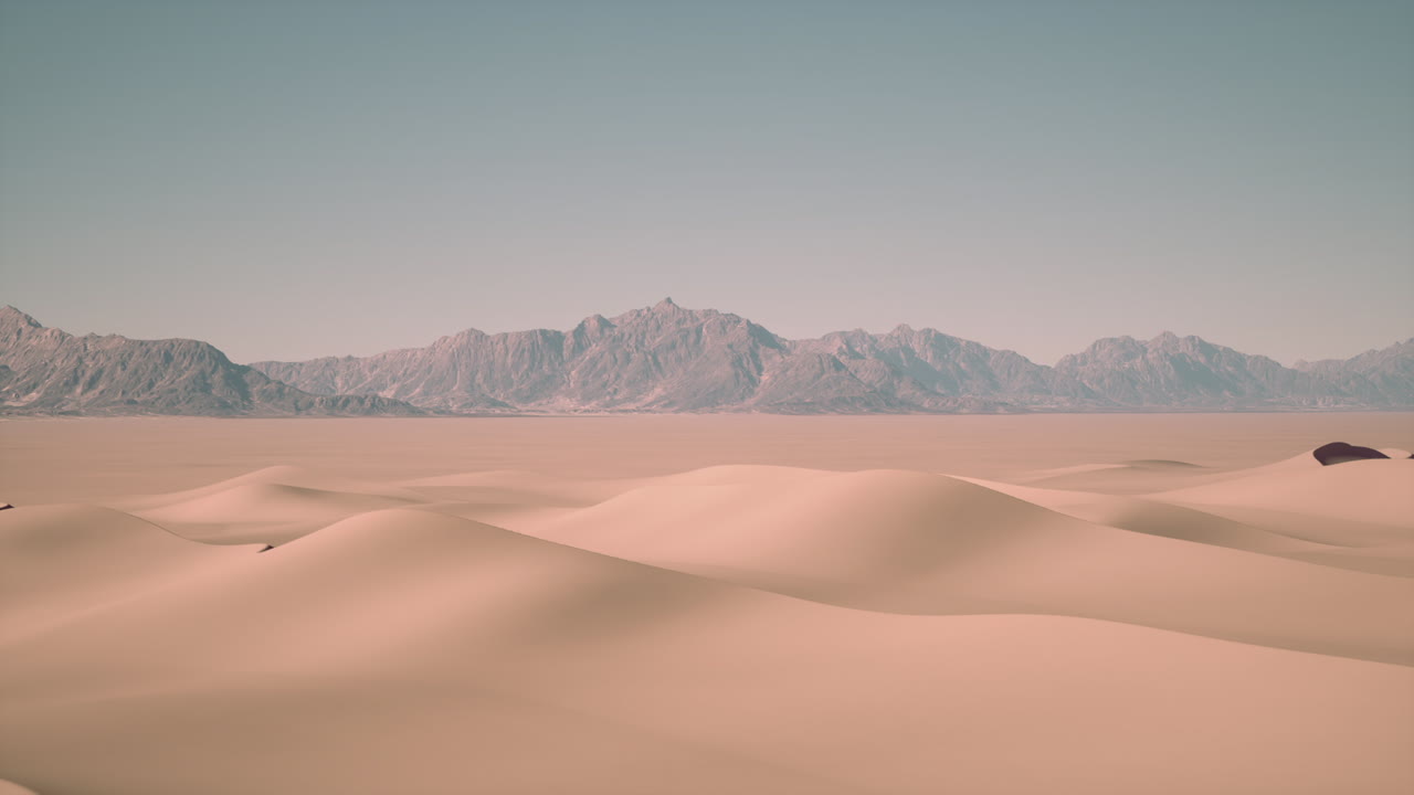 Un vasto paesaggio desertico con dune di sabbia e una catena montuosa in lontananza.