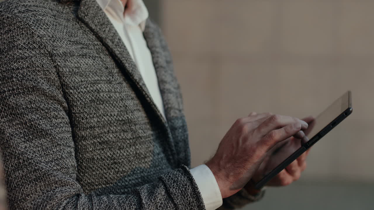 잘생긴 남자가 태블릿 컴퓨터를 두드리고 거리에서 카메라를 보고 웃고 있다