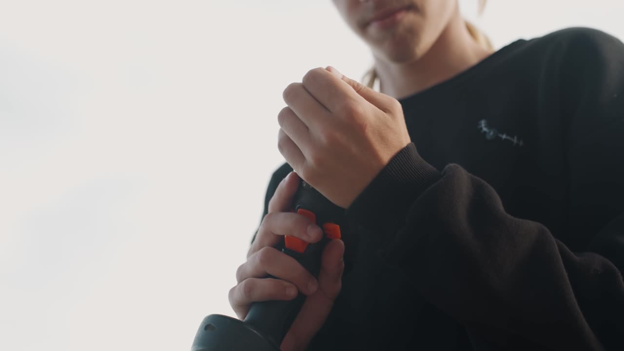 Pessoa inspecionando furadeira sem fio ao ar livre, plano médio mostrando gatilho e broca, manuseio cuidadoso, ajuste gradual, verificação da bateria, luz de fundo suave, atmosfera de tutorial prático, trabalho preciso com os dedos