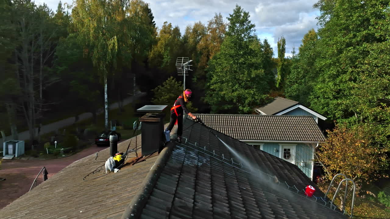 Person Cleaning Residential Roof Tiles with a Pressure Washer