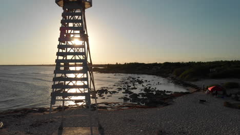 Sunset-drone-shot-of-a-lighthouse-on-the-beach-of-Mexico