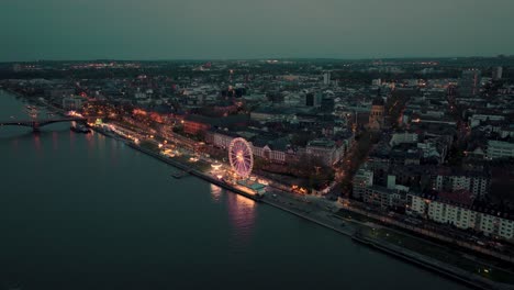 Drone-Luftaufnahme-Weit-Von-Mainz-Näher-Kommend-Zeigt-Ein-Sommernachtsweinfest-Am-Rheinufer-Mit-Vielen-Lichtern-Im-Sonnenuntergang-Mit-Der-Christuskirche-Und-Dem-Dom