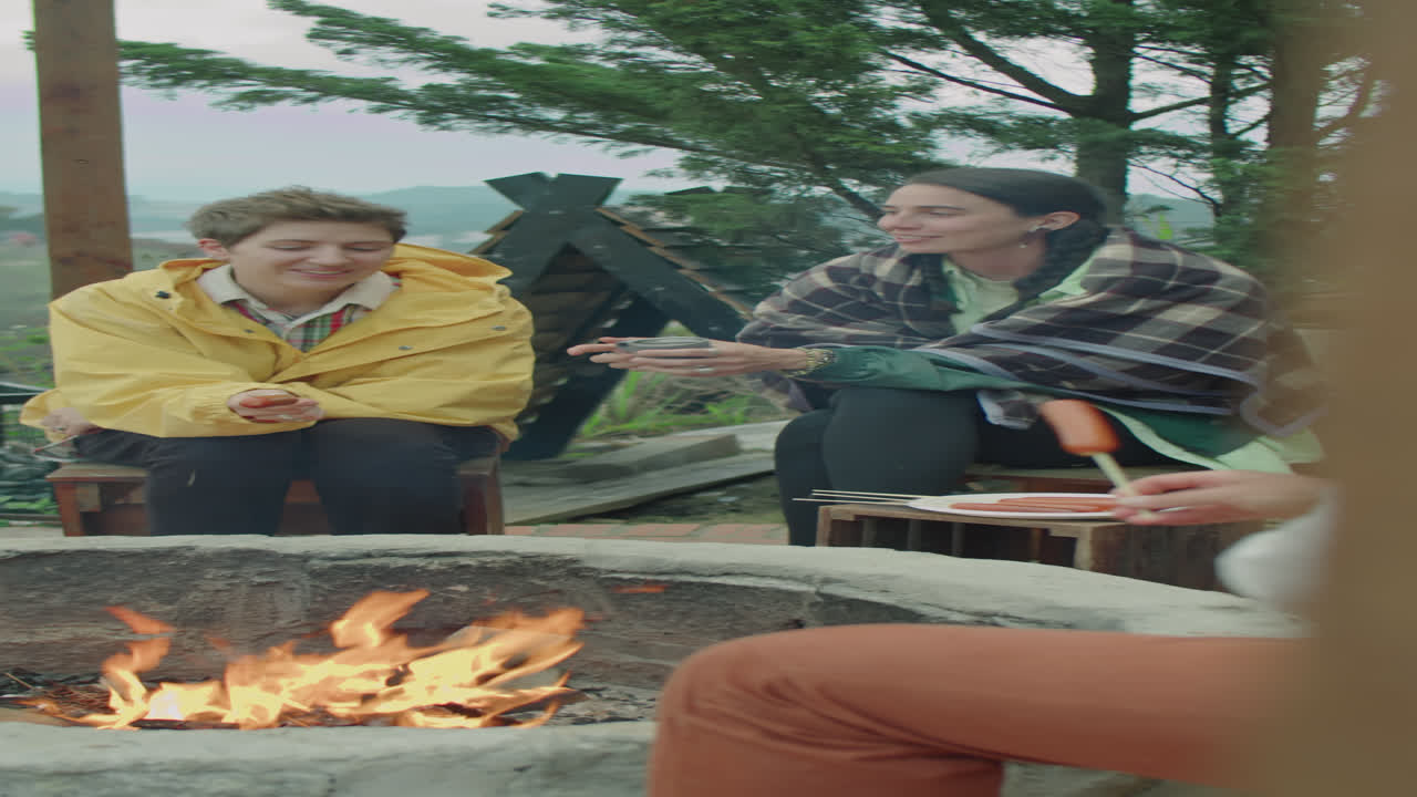 Girlfriends Chatting by Campfire on Glamping