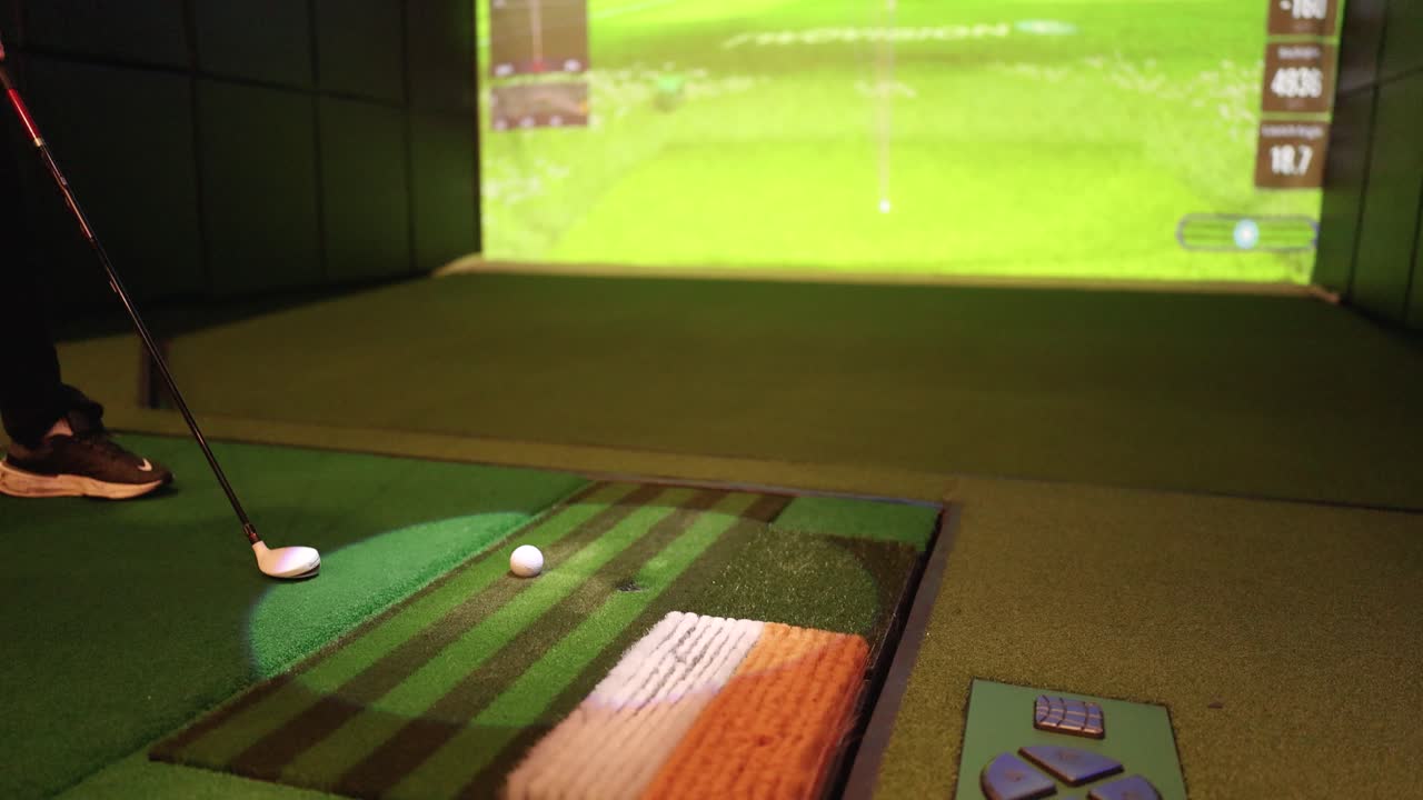 Golfer lines up indoor putt on virtual simulator green with stable, low-angle camera framing