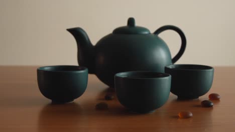 minimal background of a green japanese tea set with steam coming out of the cups, on a wooden table, with some stones around