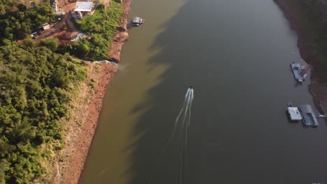 Toma-Aérea-De-Arriba-Hacia-Abajo-De-La-Lancha-Rápida-Que-Cruza-El-Río-Iguazú-Durante-El-Día-Soleado-En-América-Del-Sur