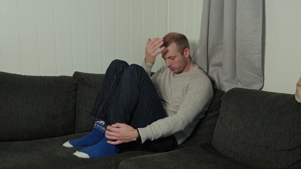 Homem deprimido, angústia emocional no canto do sofá