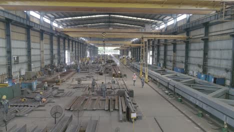 metalworkers busy working in a steel fabrication plant. high angle