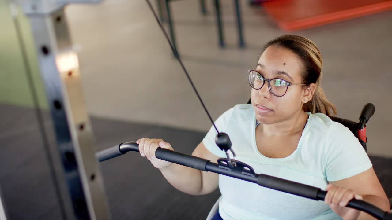 woman in wheelchair with paraplegia exercising with cable machine in rehabilitation gym