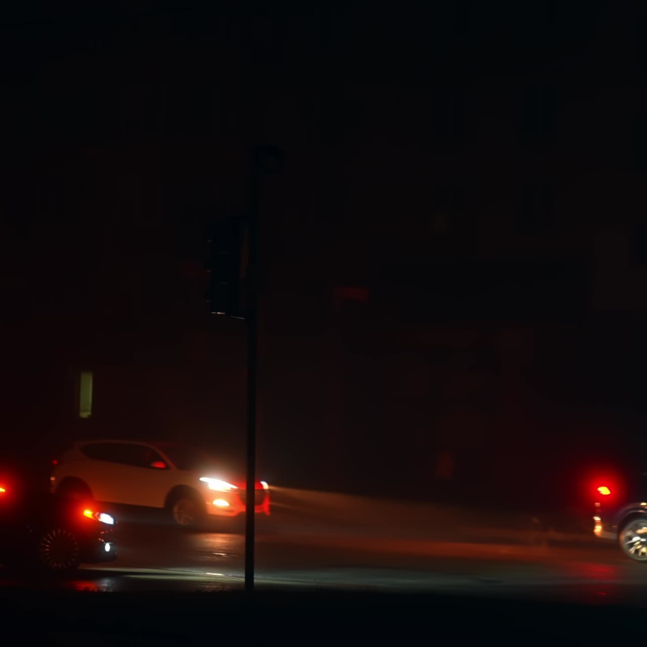 Cars riding with lights on by the dark street of Kyiv. Shortage in electricity resulting in power outage for long hours