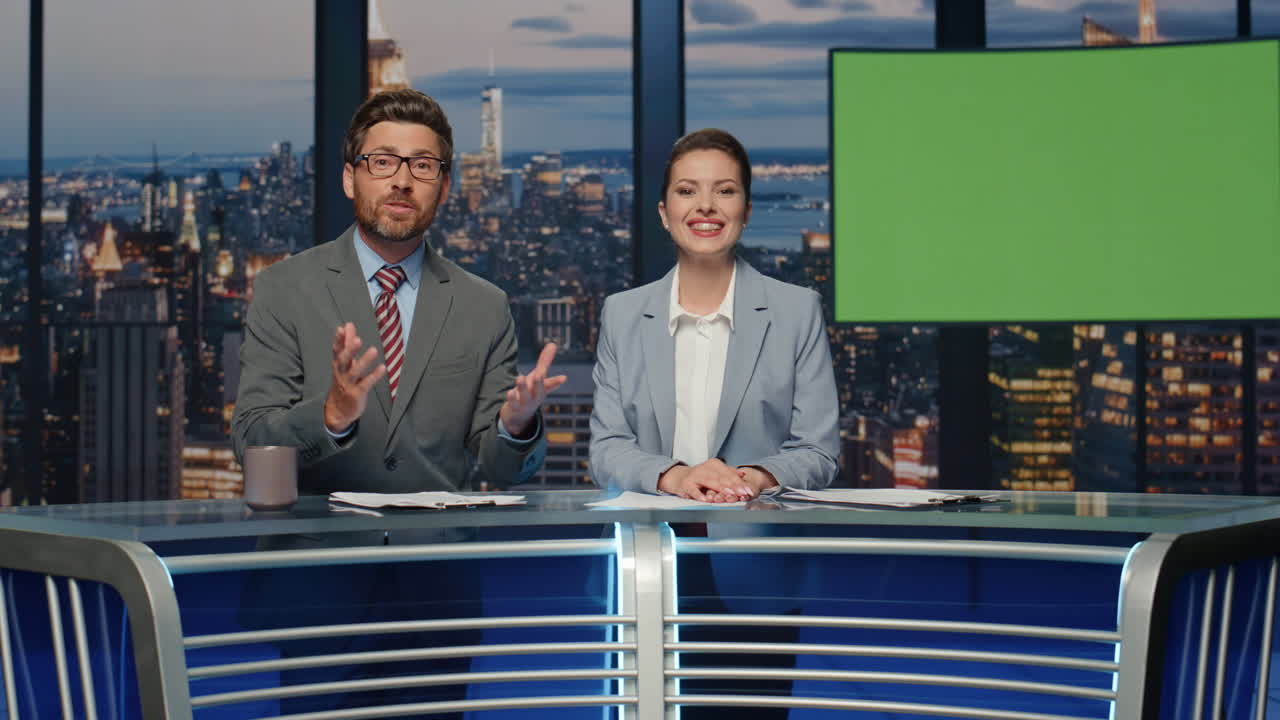 una pareja de presentadores discutiendo noticias simuladas en el primer plano de la televisión nocturna. los presentadores sonriendo