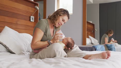 Video-Einer-Glücklichen-Kaukasischen-Mutter,-Die-Ihr-Neugeborenes-Baby-Mit-Der-Flasche-Auf-Dem-Bett-Füttert