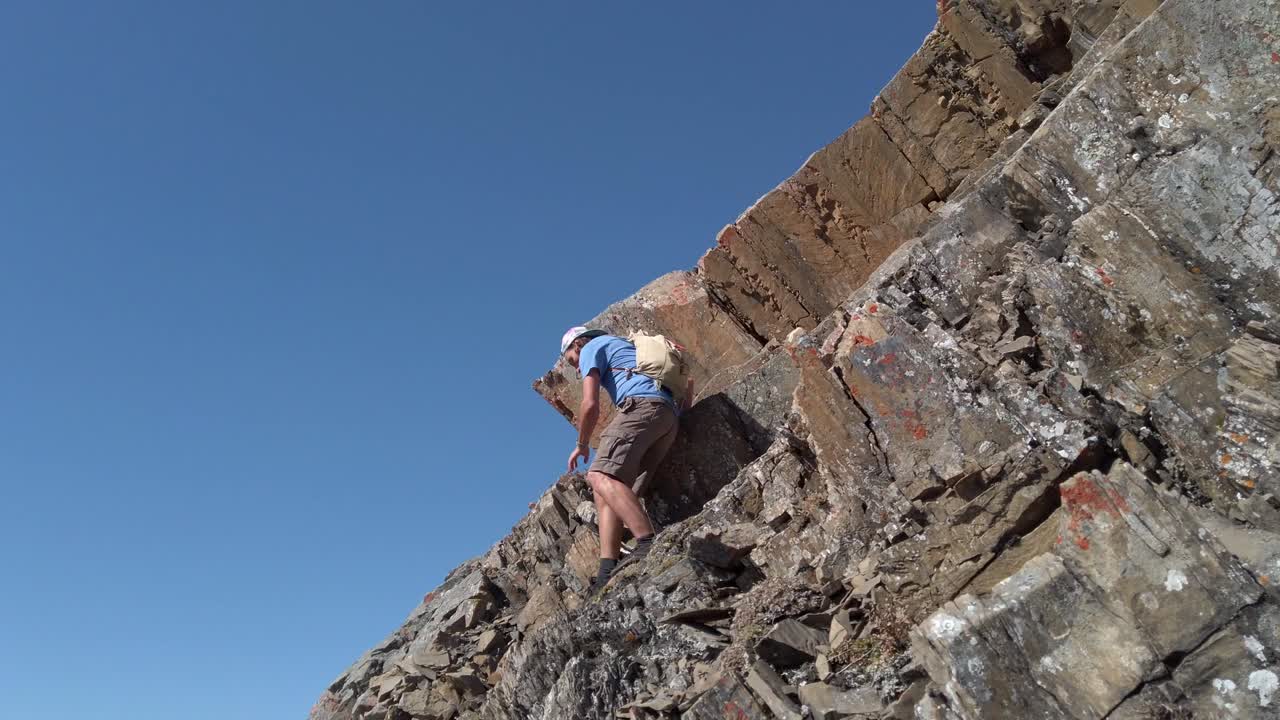 excursionista bajando con cuidado por la montaña rocosa en ángulo bajo en cámara lenta en un círculo seguido de kananaskis, alberta, canadá