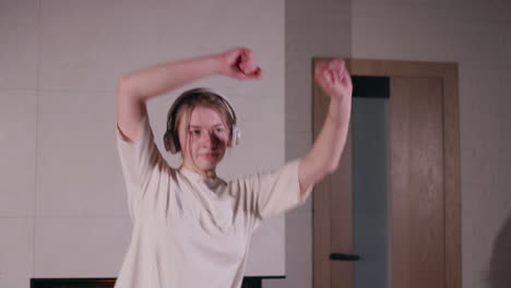 mujer joven bailando en casa con auriculares