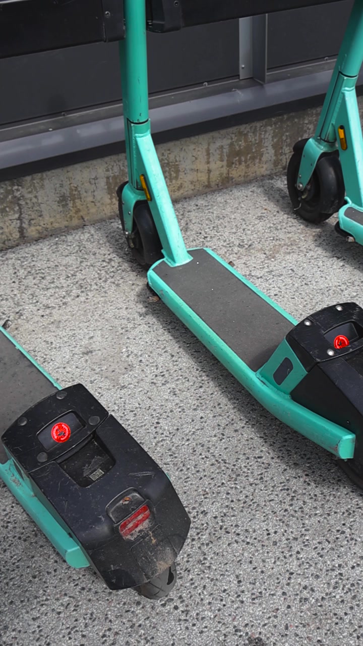 Monopattini elettrici in sharing parcheggiati in fila su un marciapiede urbano, simbolo di mobilità sostenibile, micromobilità e soluzione di trasporto moderna a noleggio tramite app mobile.