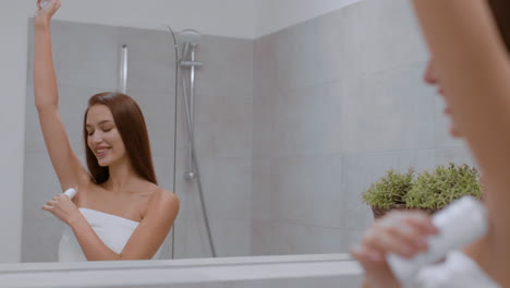 woman applying deodorant in the bathroom