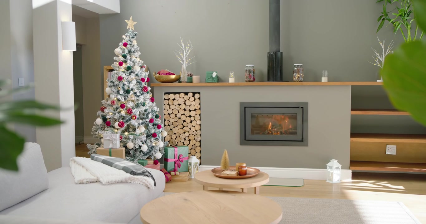 La telecamera sta panoramando, rivelando un albero di Natale innevato e un camino acceso per mostrare l'arredamento del soggiorno