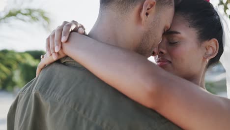 happy diverse bride and groom embracing at beach wedding, in slow motion