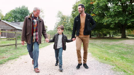 abuelo con hijo y nieto en otoño caminando juntos por el campo