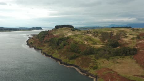 aerial drone panoramic fly over shot.  backwards motion. beautiful scotland highlands. remote rural area, green fields, forests with sea, loch lake and mountains in the background. 4k footage.