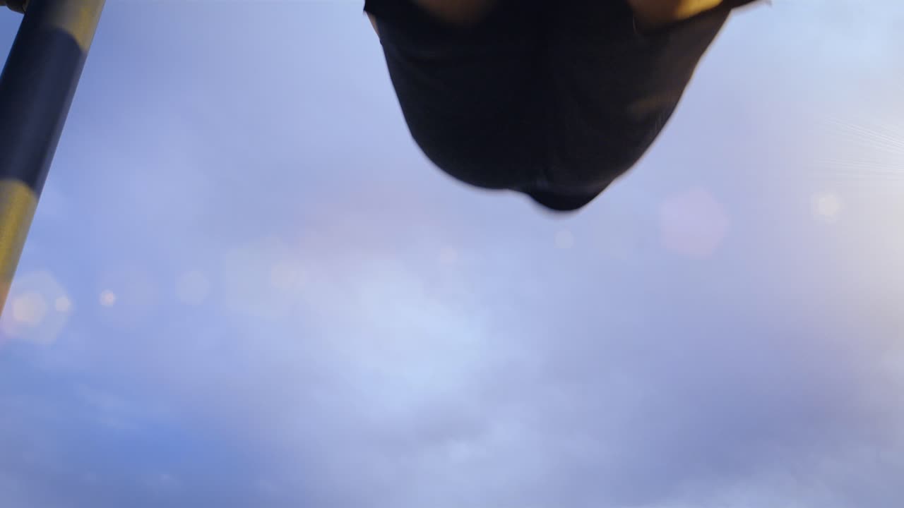 야외 체육관에서 풀업 바에서 운동을 하는 운동선수의 추적 샷