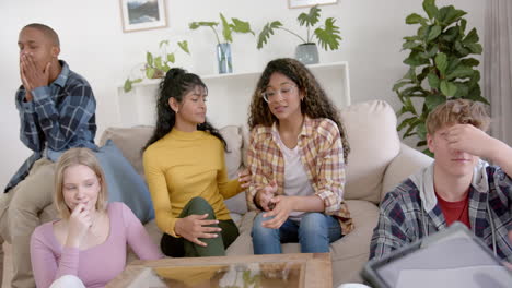 Diverse-group-of-teenage-friends-using-tablet-with-copy-space-and-embracing-at-home,-slow-motion