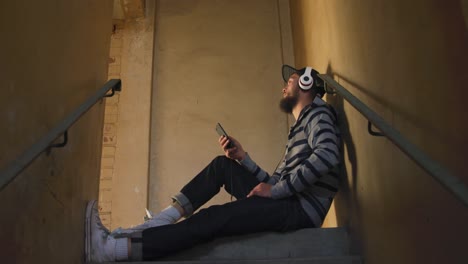 young man listening to music in empty warehouse