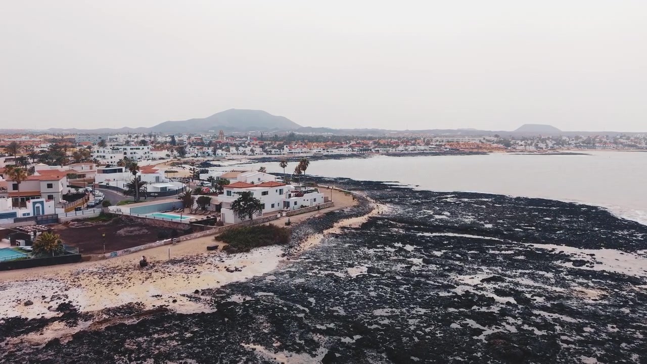 Vista aérea de un pueblo costero con una costa de roca volcánica